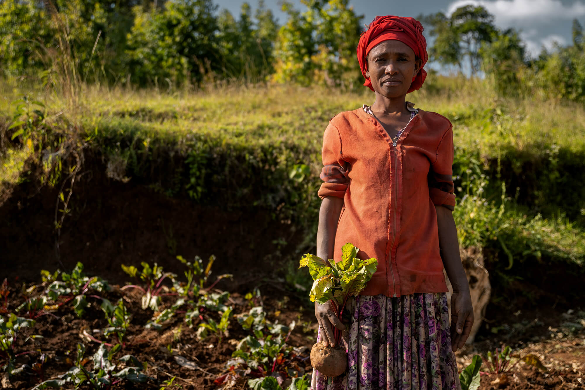 Eshale stands in her backyard garden, where she grows a variety of crops to support her large family.